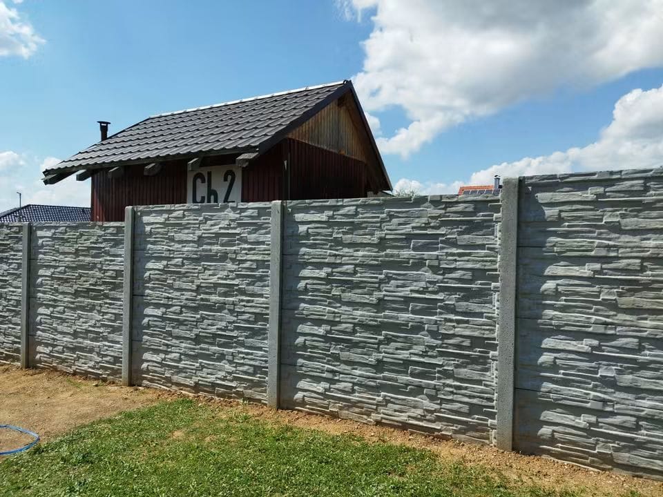 Šedý betonový plot se skládaným kamenným dekorem u rodinného domu